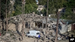 People look at the destroyed houses a day after shelling by Armenian's artillery during fighting over the separatist region of Nagorno-Karabakh, in Ganja, Azerbaijan, Oct. 12, 2020.