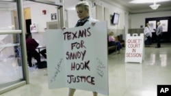 Kelly Jones, ex-wife of Infowars host Alex Jones, carries a sign as she arrives at the Travis County Courthouse, Aug. 1, 2018, in Austin, Texas. Alex Jones wants a Texas judge to dismiss a defamation lawsuit filed against him by families of some of the children killed in the 2012 mass shooting at Sandy Hook Elementary School.