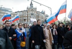 FILE - Russian opposition activist Alexei Navalny, center, his wife Yulia, right of him, and opposition activist Lyubov Sobol, second from left, take part in a march in memory of opposition leader Boris Nemtsov in Moscow, Feb. 29, 2020.