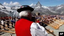 Alphorn blowers in Zermatt play together on the Gornergrat Mountain with the Matterhorn mountain in the background.