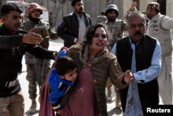 FILE - A policeman guides a family away from the Bethel Memorial Methodist Church in Quetta, Pakistan, after gunmen attacked, Dec. 17, 2017.