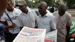 People read newspapers with election headlines on the street in Abuja, Nigeria Monday, March 30, 2015. Nigerians are waiting for results of the tightest and most bitterly contested presidential election in the nation's turbulent history. (AP Photo/Sunday Alamba)
