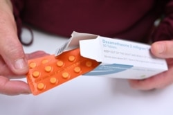 A pharmacist holds a box of dexamethasone tablets at a chemists shop in London, June 16, 2020.