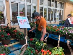 A worker wearing a mask to protect against the coronavirus waters plants at a Joe Randazzo’s store in Roseville, Mich., Saturday, May 2, 2020.