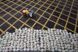 2020年2月26日骑车人经过湖北省武汉市一条街道上准备运送的蔬菜