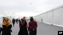 FILE - Afghan refugees walk alongside temporary housing in Liberty Village on Joint Base McGuire-Dix- Lakehurst in Trenton, N.J., Dec. 2, 2021.