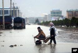 Afghans make their way in flooded water from heavy rain in Kabul, Afghanistan, April 2, 2016.