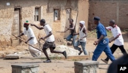 FILE - Members of the Imbonerakure pro-government youth militia chase after opposition protesters, unhindered by police, in the Kinama district of the capital Bujumbura, Burundi on May 25, 2015.