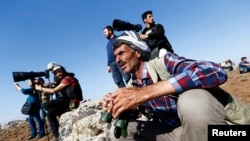Turkish Kurds watch the Syrian town of Kobani from a hill near the Mursitpinar border crossing, in Suruc, Oct. 24, 2014. 