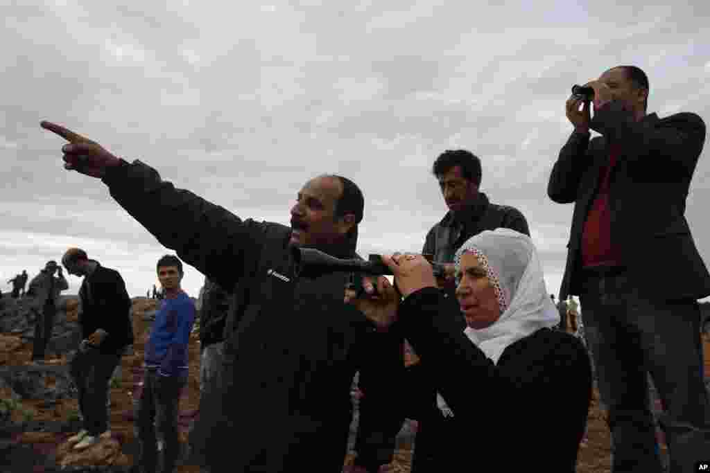People gather on a hilltop on the outskirts of Suruc, at the Turkey-Syria border, to watch the fighting between Syrian Kurds and the militants of Islamic State group in Kobani, Syria, Oct. 19, 2014.