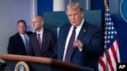 President Donald Trump speaks, accompanied by Food and Drug Administration Commissioner Dr. Stephen Hahn, center, during a media briefing in the James Brady Briefing Room of the White House, Aug. 23, 2020, in Washington.