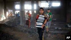 Palestinians carry books they salvaged from a mosque in Zeitoun neighborhood in Gaza City, after it was hit by an Israeli airstrike, Saturday, Aug. 9, 2014.