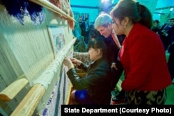 Kerry, center, examines weaving of a traditional silk carpet at Registan in Samarkand, Uzbekistan, spotlighting the importance of cultural preservation, Nov. 1, 2015.