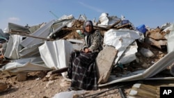 A Bedouin woman sit on demolished structure of a house in the Bedouin village of Umm al-Hiran, near the southern city of Beersheba, Israel Wednesday, Jan. 18, 2017.