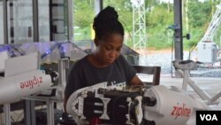 Flight operator Josephine Fianu checks over a Zipline drone before sending it out for a delivery from the Omenako drone center, in Ghana. (S. Knott/VOA)