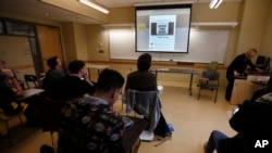 FILE - Students in a journalism course at Kean University in Union, N.J., watch a presentation on fake news, Jan. 20, 2017. Teachers from elementary school through college have been ramping up media literacy training to recognize bogus reports and understand their potential to weaken civic culture. 