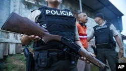 ARCHIVO - Un agente de policía hace guardia mientras una persona es detenida durante un registro en busca de armas o drogas, dentro de una operación para luchar contra las bandas criminales, en el vecindario de Nueva Guayaquil, en Guayaquil, Ecuador, el 4 de abril de 2024. 