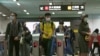 FILE - People wearing face masks to protect against the spread of the coronavirus go through gates of a metro in Taipei on Dec. 29, 2020. 
