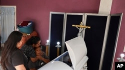 Martha Alvarado, seated, is comforted in her home in Irapuato, Mexico, July 2, 2020, during the wake of her son Jorge Bravo who was killed in an attack at a drug rehabilitation center where he was being treated. 