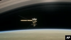 This image made available by NASA in April 2017 shows a still from the short film "Cassini's Grand Finale," with the spacecraft diving between Saturn and the planet's innermost ring. 
