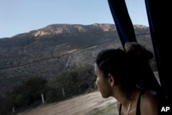 FILE - A Central American migrant looks out toward the border with the U.S., between Mexicali and Tijuana, as she rides by bus with a caravan of migrants to Tijuana, Mexico, April 26, 2018.