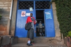 FILE - A student's temperature is measured by a staff member at Valley View Academy school in the Mathare slum in Nairobi, Kenya, Jan. 4, 2021, as students return to school following a nine-month closure ordered by the government in March.