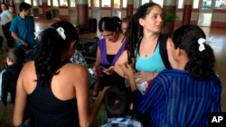 FILE - Volunteer Layal Rabat from the Phoenix Restoration Project brings water, food and diapers to Central-American women and their children dropped off at the Greyhound bus station in Phoenix, May 29, 2014.