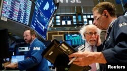 FILE - Traders work on the floor of the New York Stock Exchange (NYSE) in New York, March 29, 2018. With U.S. stocks slumping, investors worry about President Donald Trump's attacks on giant online retailer Amazon and China's retaliatory imposition of tariffs on U.S. products.