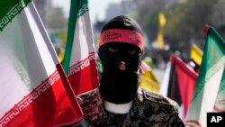 Seorang anggota kelompok paramiliter Basij, yang terkait dengan Garda Revolusi Iran (IRGC), membawa bendera Iran dalam aksi tahunan memperingati Hari Quds atau Hari Yerusalem, di Teheran, Iran, pada 5 April 2024. (Foto: AP/Vahid Salemi)