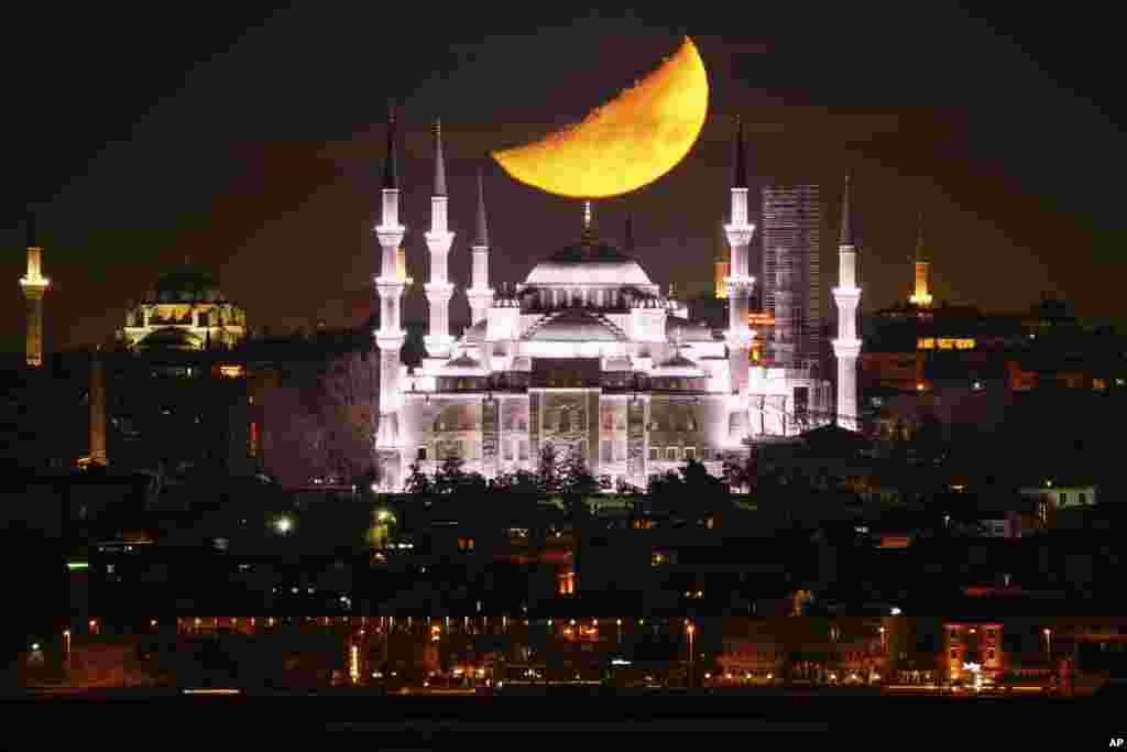 A half-moon sets behind the Sultanahmet Mosque during the Islamic holy month of Ramadan in Istanbul, Turkey.