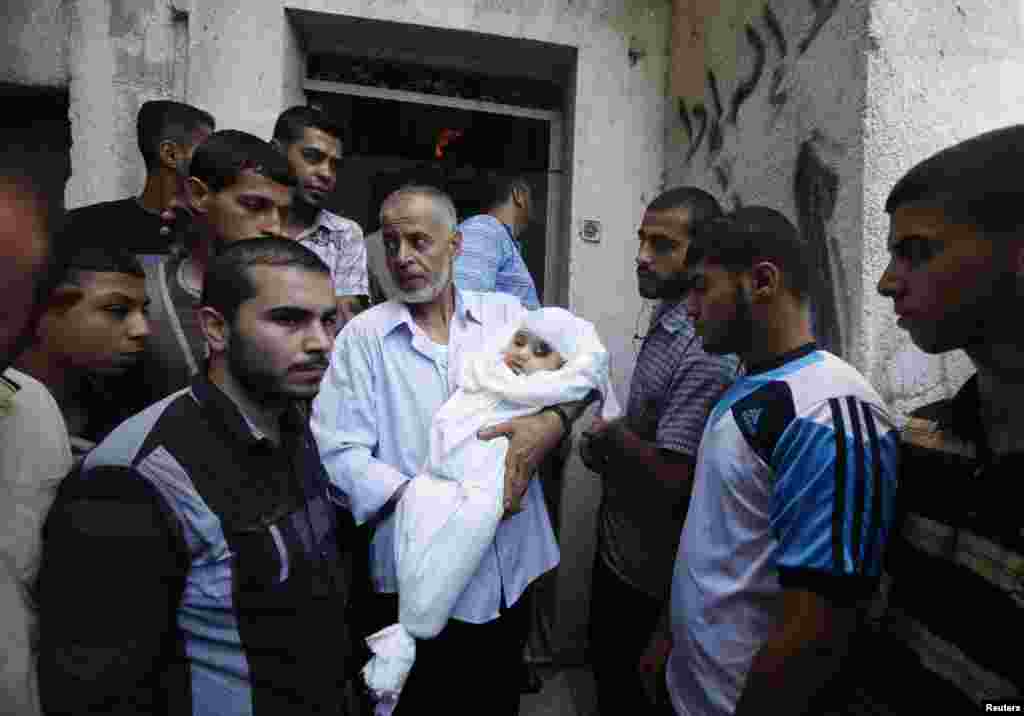 A relative of the wife of Hamas's military leader, Mohammed Deif, and his infant son Ali, whom medics said were killed in Israeli air strikes, carries Ali's body during the funeral, in the northern Gaza Strip, Aug. 20, 2014.