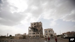 People stand by a building destroyed by a Saudi-led airstrike in Sana'a, Yemen, July 6, 2015. 