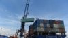 FILE - Containers are transferred from a truck to a cargo ship at the international cargo terminal of a port in Hai Phong, Vietnam, Aug. 12, 2019.