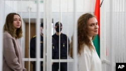 Journalists Katsiaryna Andreyeva, right, and Daria Chultsova stand inside a defendants' cage in a court room in Minsk, Belarus, Feb. 18, 2021. 