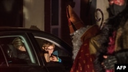 Members of circus company Cirk La Putyka, dressed as Saint Nicholases, entertain people during their drive-through performance, Dec. 5, 2020 in Prague.