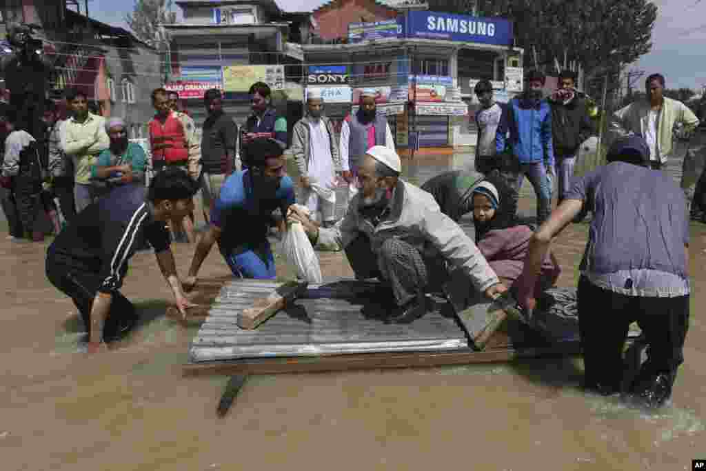 Kashmiri men use a makeshift raft to evacuate an elderly man and his grand daughter from a flooded neighborhood in Srinagar, India, Sept. 7, 2014.