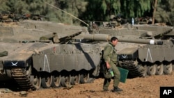 FILE - An Israeli soldier walks past tanks near the Israel and Gaza border, July 10, 2014. 