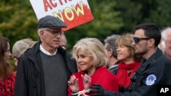 Actress and activist Jane Fonda, joined at left by actor Ted Danson, is arrested at the Capitol for blocking the street after she and other demonstrators called on Congress for action to address climate change, in Washington, Oct. 25, 2019.