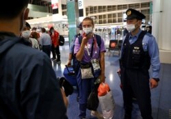 Belarusian sprinter Krystsina Tsimanouskaya is escorted by police officers at Haneda international airport in Tokyo, Japan, Aug. 1, 2021.