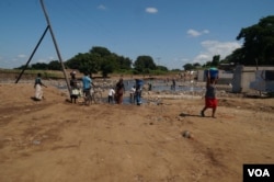 Residents of the heaviest-hit southern areas draw water from small rivers created by the floods. (L. Mesina for VOA)