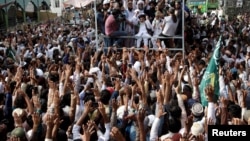 Supporters of the Tehreek-e-Labbaik Pakistan (TLP) Islamist political party raise their hands as they listen to the speech of their leader during a protest march to condemn a cartoon competition in the Netherlands, in Lahore, Pakistan, Aug. 29, 2018. 