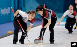 South Korea's Kim Seonyeong, left, sweeps ice with a teammate during their match against Russian athletes at the 2018 Winter Olympics in Gangneung, South Korea, Feb. 21, 2018.