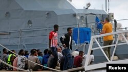 FILE - A police officer speaks to rescued migrants after they arrived on an Armed Forces of Malta patrol boat in Valletta's Marsamxett Harbor, Malta, Sept. 21, 2019. 