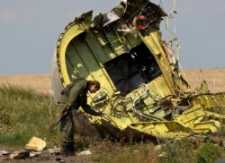 FILE - In this July 22, 2014 file photo, a pro-Russian rebel touches the MH17 wreckage at the crash site of Malaysia Airlines Flight 17, near the village of Hrabove, eastern Ukraine.