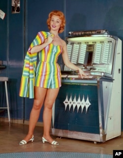 In this 1964 photo, a model stands next to a jukebox.