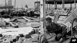 This Aug. 19, 1969 photograph showing Carl Wright, 11, drinking from a broken pipe amid the ruins of his father's service station in Gulfport, Miss., in the aftermath of Hurricane Camille.