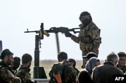 Fighters with the U.S.-backed Syrian Democratic Forces (SDF) gather at a scanning area for people who are evacuated from the Islamic State (IS) group's embattled holdout of Baghouz, during an operation in the eastern Syr