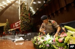 FILE - Members of a police bomb squad search for suspicious materials in December 2014, prior to the Christmas Eve Mass in Jakarta, Indonesia. Nine recent arrests foiled a year-end terror plot, Indonesia’s police chief said Monday.