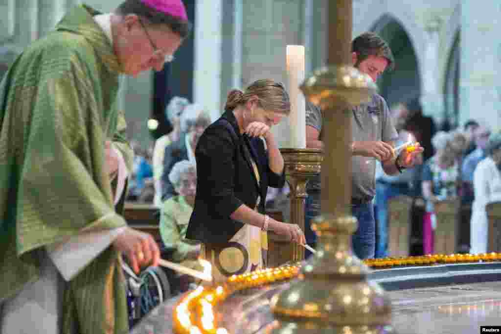 Churchgoers together with bishop Jan Hendriks (L) light some 298 candles, representing the victims of the crashed Malaysia Airlines Flight MH17 plane, before a mass in the Saint Bavo cathedral in Haarlem, the Netherlands, July 20, 2014.