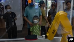 Visitors watch a robot arm play ping-pong at the China Beijing Hi-Tech Expo in Beijing, July 16, 2024.